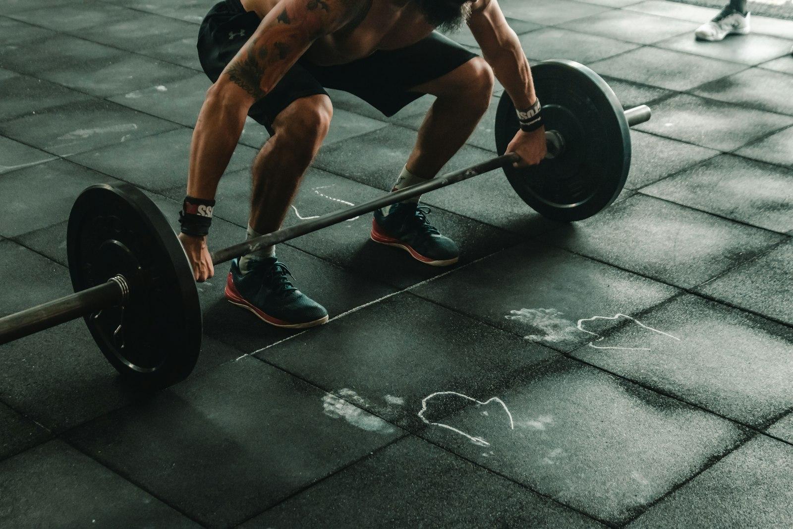 An athlete gripping a loaded barbell on a gym floor